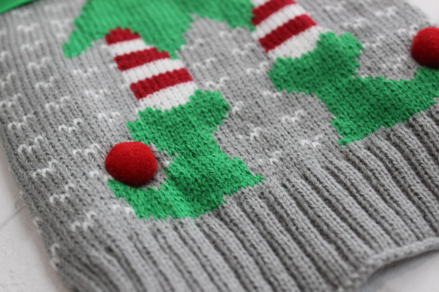 Close up of knitted fabric and red pom poms attached at shoes.