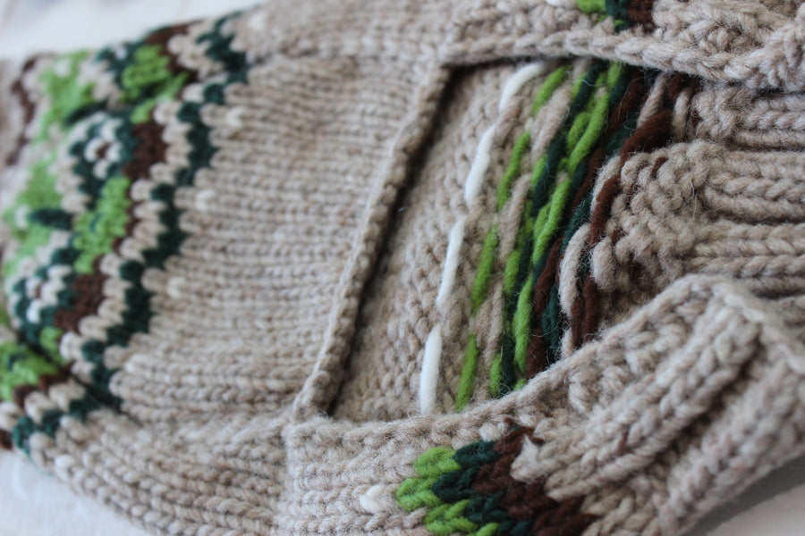 Dog sweater crocheted with green, brown and tan colors, showing underside at belly and inside of woven dog sweater.